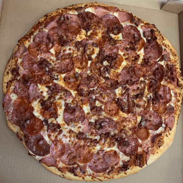 A 7th Street Pizza pepperoni and sausage pizza, with melted cheese and a golden crust, in a box.