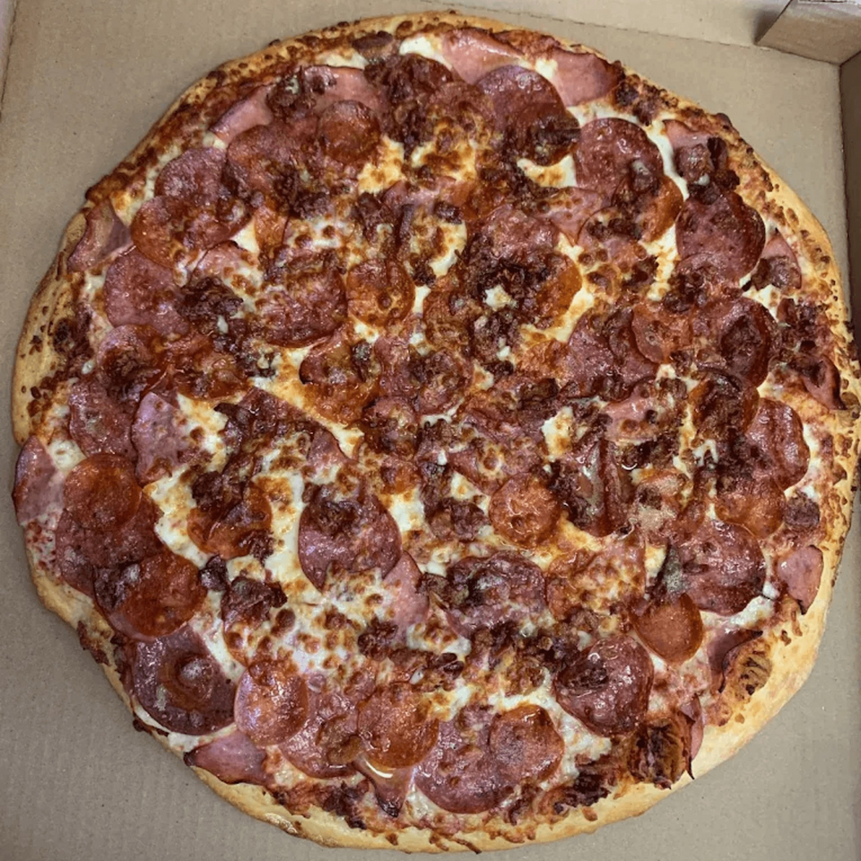 A 7th Street Pizza pepperoni and sausage pizza, with melted cheese and a golden crust, in a box.